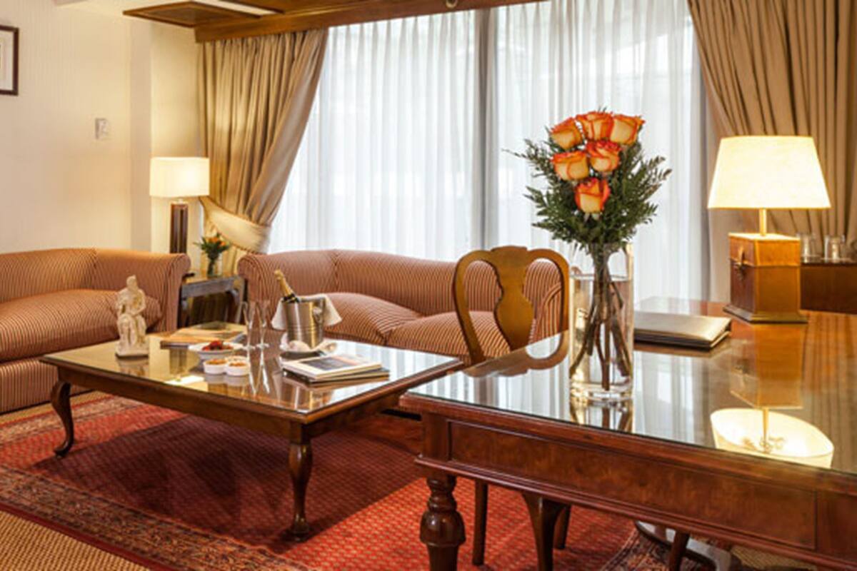 A living room with a sofa, a coffee table, a chair, a vase with flowers, and two lamps.