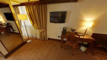 Habitación de hotel con un espejo grande, un escritorio con silla, un televisor y una lámpara.