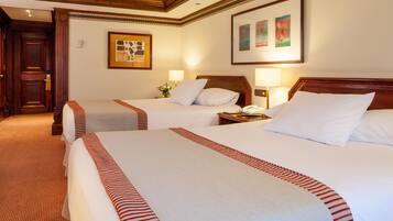 A hotel room with two beds, each with a red-striped bedspread, a wooden headboard, and a nightstand with a lamp.