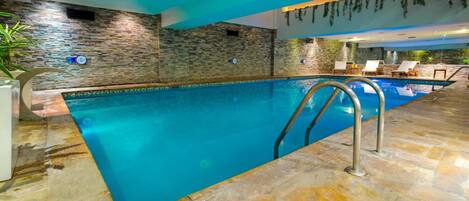 An indoor swimming pool with stone walls and a tiled floor.