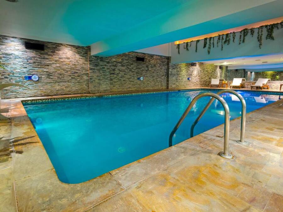 Una piscina interior con paredes de piedra y suelo de baldosas.