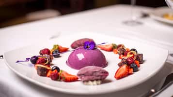 A dessert plate with various fruits and a purple dessert centerpiece.