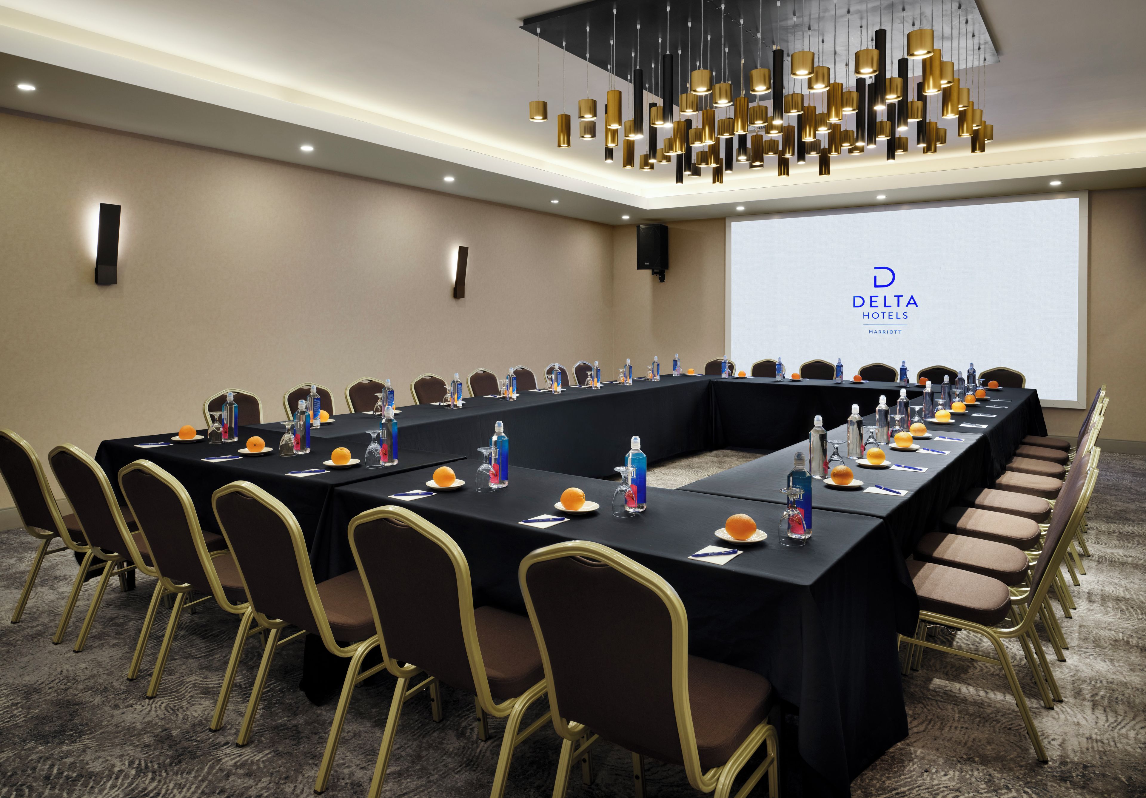 Une salle de conférence avec une longue table, des chaises et un écran de projection sur lequel est affiché le logo de Delta Hotels.