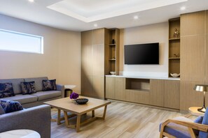 A modern living room with a sofa, coffee table, and TV mounted on a wooden wall.