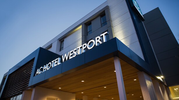 ACHOTEL WESTPORT -rakennuksen ulkoasu: siinä on selkeästi näkyvä kyltti, moderni arkkitehtuuri ja taustalla kirkas taivas.