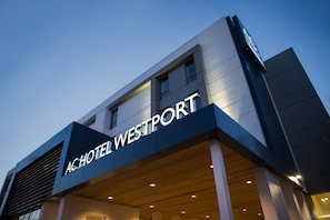 ACHOTEL WESTPORT -rakennuksen ulkoasu: siinä on selkeästi näkyvä kyltti, moderni arkkitehtuuri ja taustalla kirkas taivas.