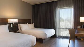A hotel room with two beds, a desk, and a chair.
