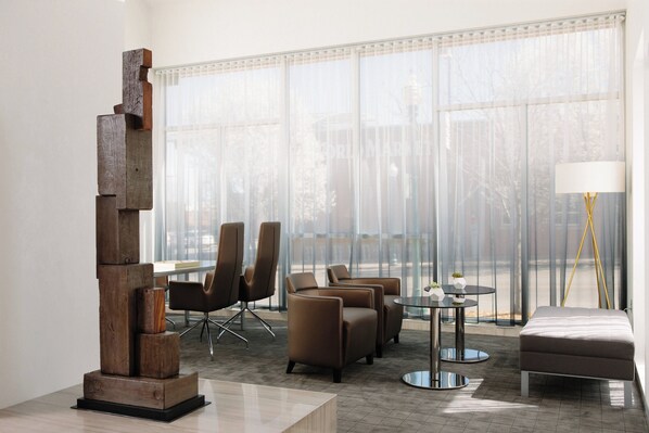 A modern living room with a wooden sculpture, leather sofas, a glass coffee table, and a lamp.