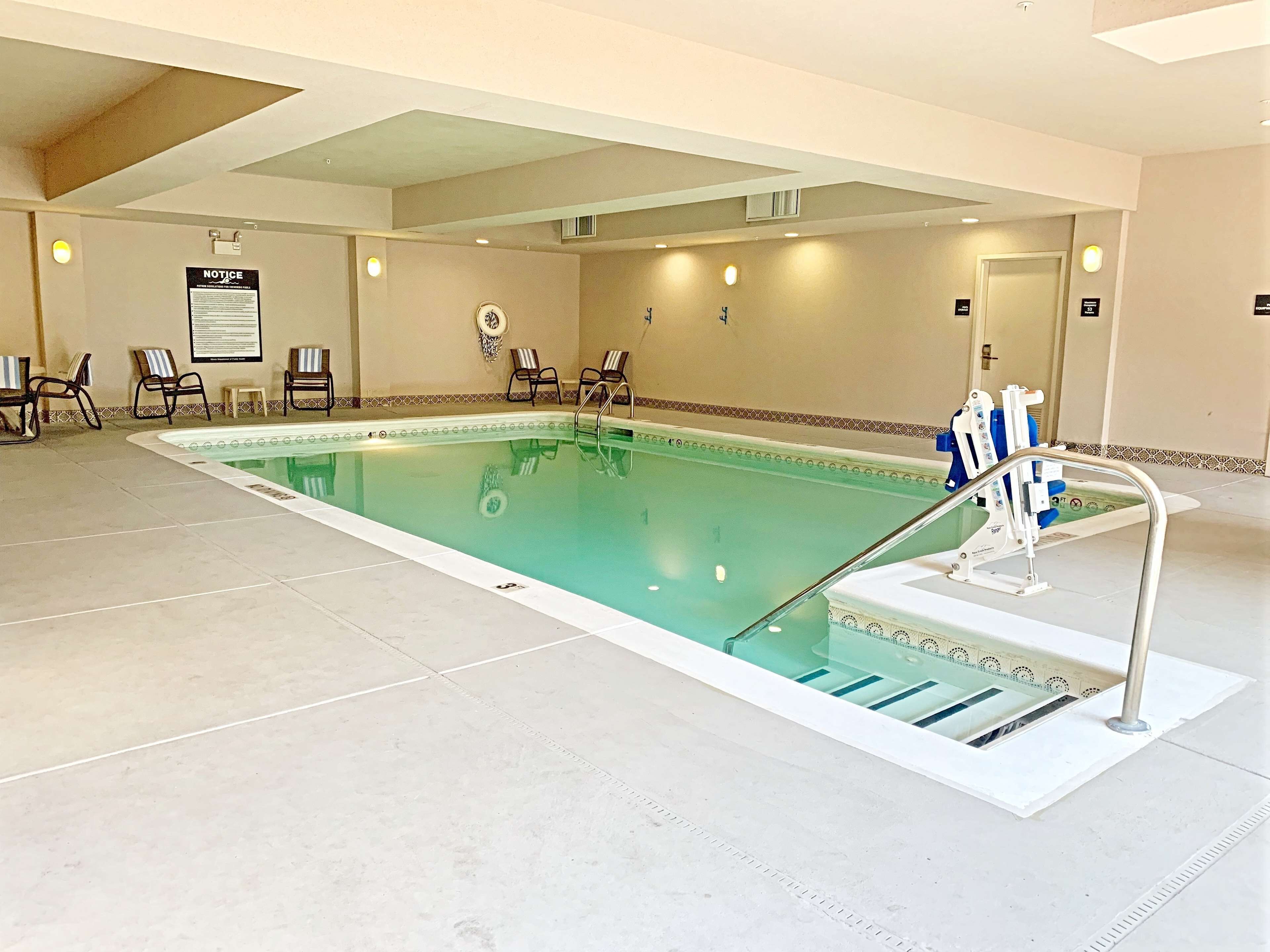 A swimming pool with a pool ladder, lounge chairs, and a notice board.