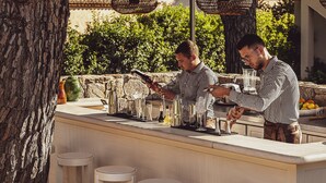 Una zona de bar con mostrador de piedra, utensilios para coctelería y taburetes.
