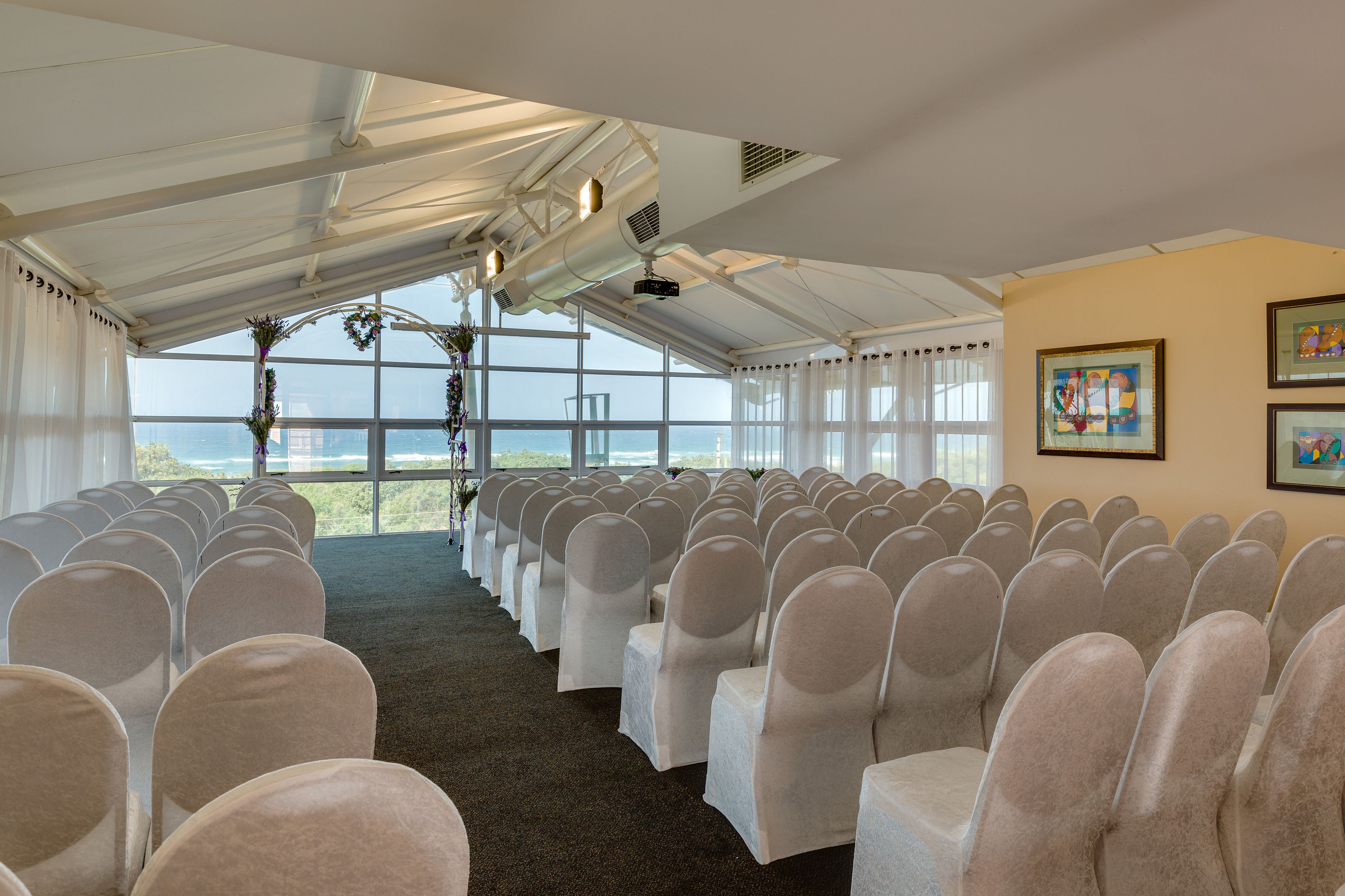 A conference room with rows of chairs, large windows, and artwork on the walls.
