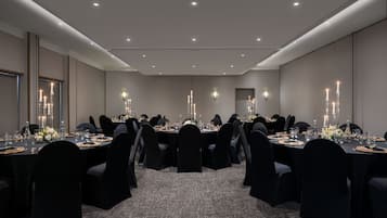 A conference room with round tables, black chairs, and candlelit centerpieces.