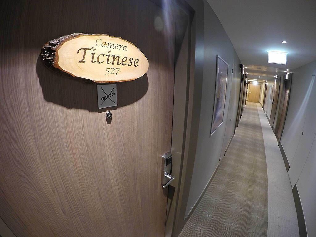 Ein Hotelgang mit einem Holzschild, auf dem 'Camara Ticinese 527' steht.