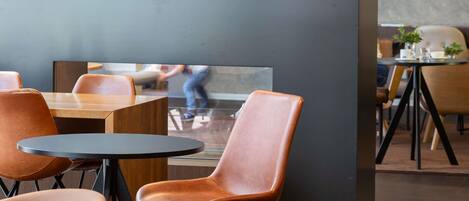 A modern restaurant interior with round tables, leather chairs, and a decorative boat model on a shelf.
