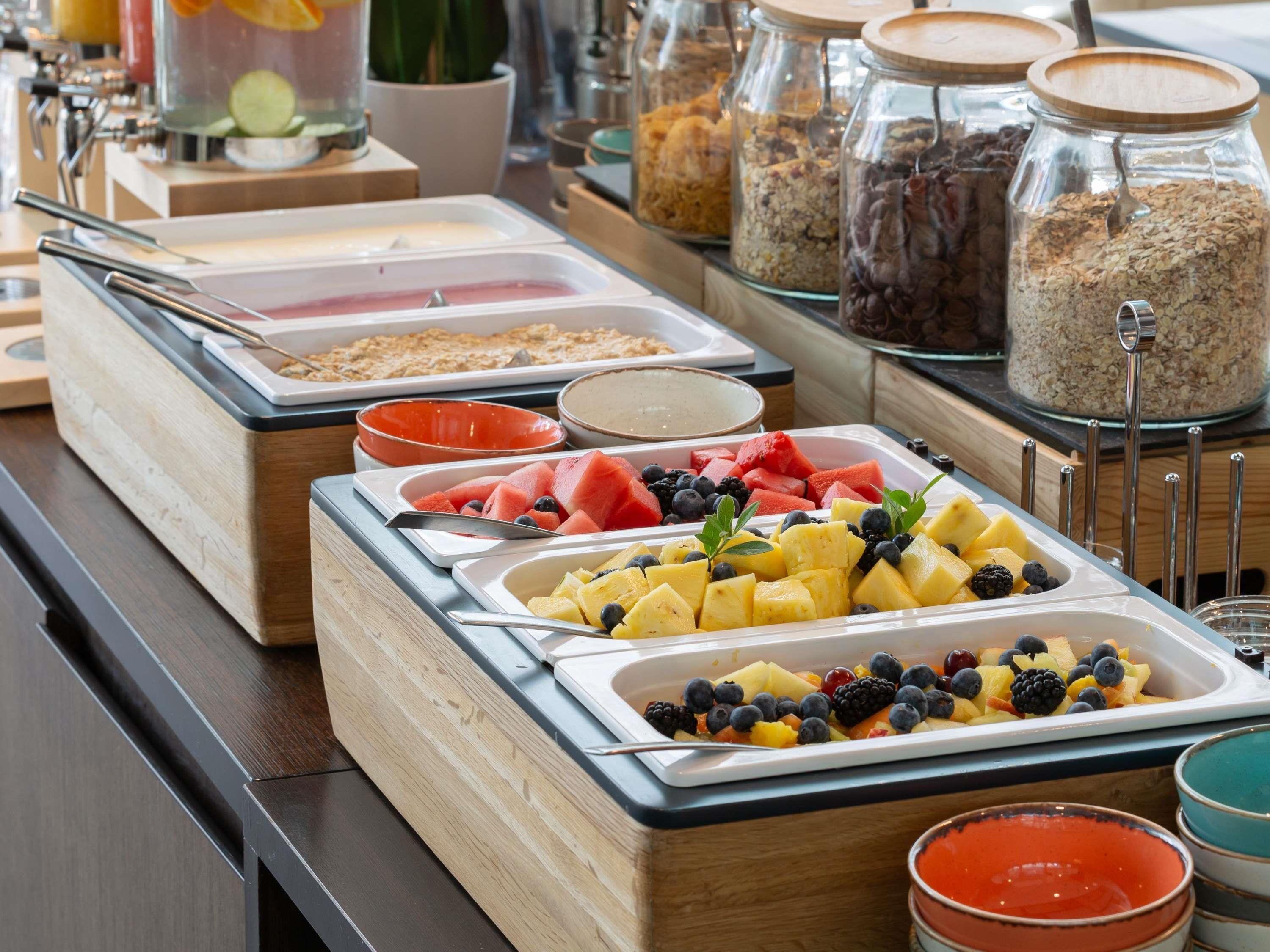 A buffet with various food options including fruits, cereals, and beverages.
