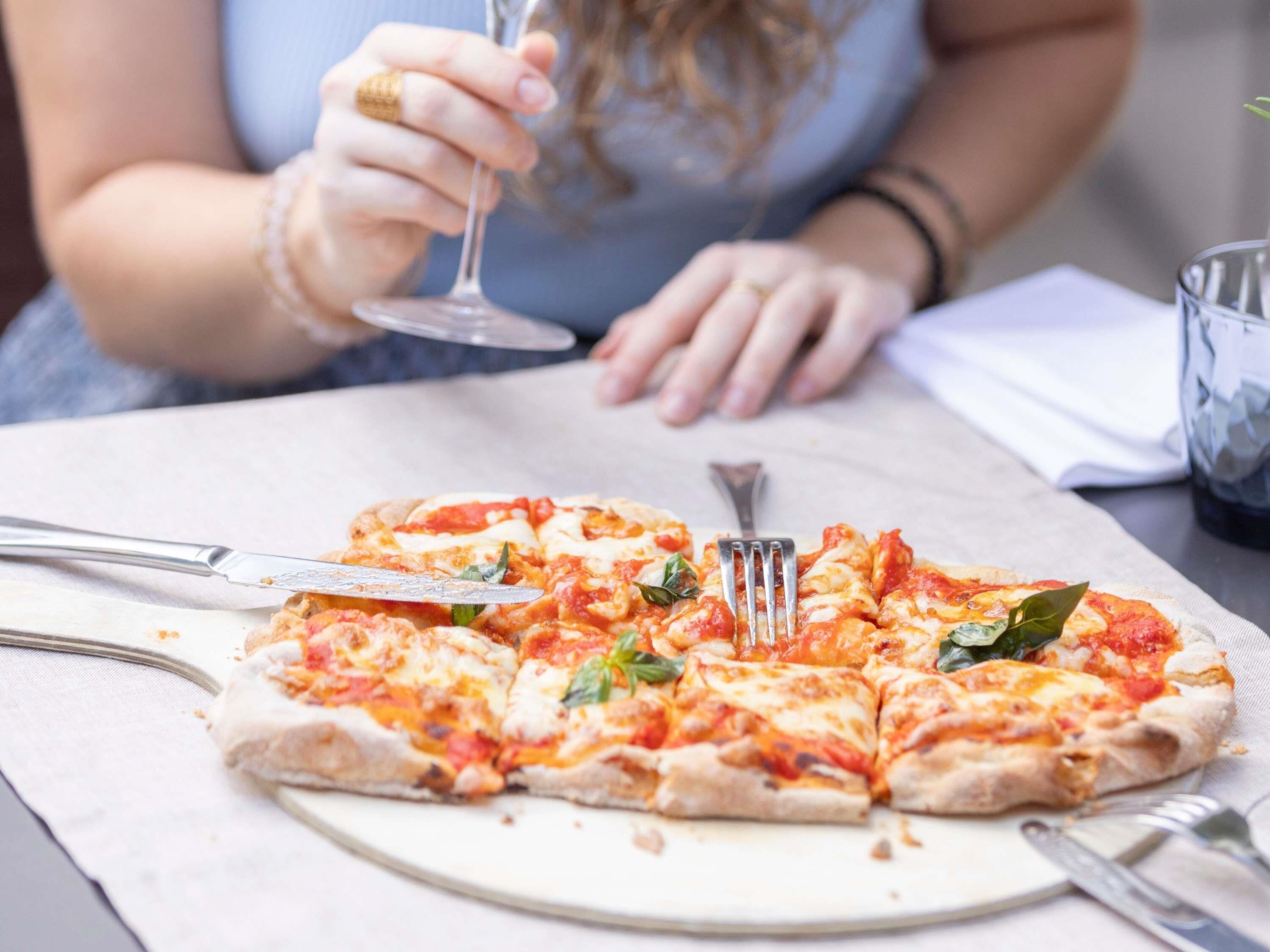 En pizza som serveras med gaffel och kniv på ett bord.