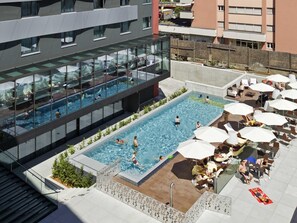 A rooftop swimming pool with glass walls, lounge chairs, and umbrellas. - Novotel Lugano Paradiso (Paradiso)