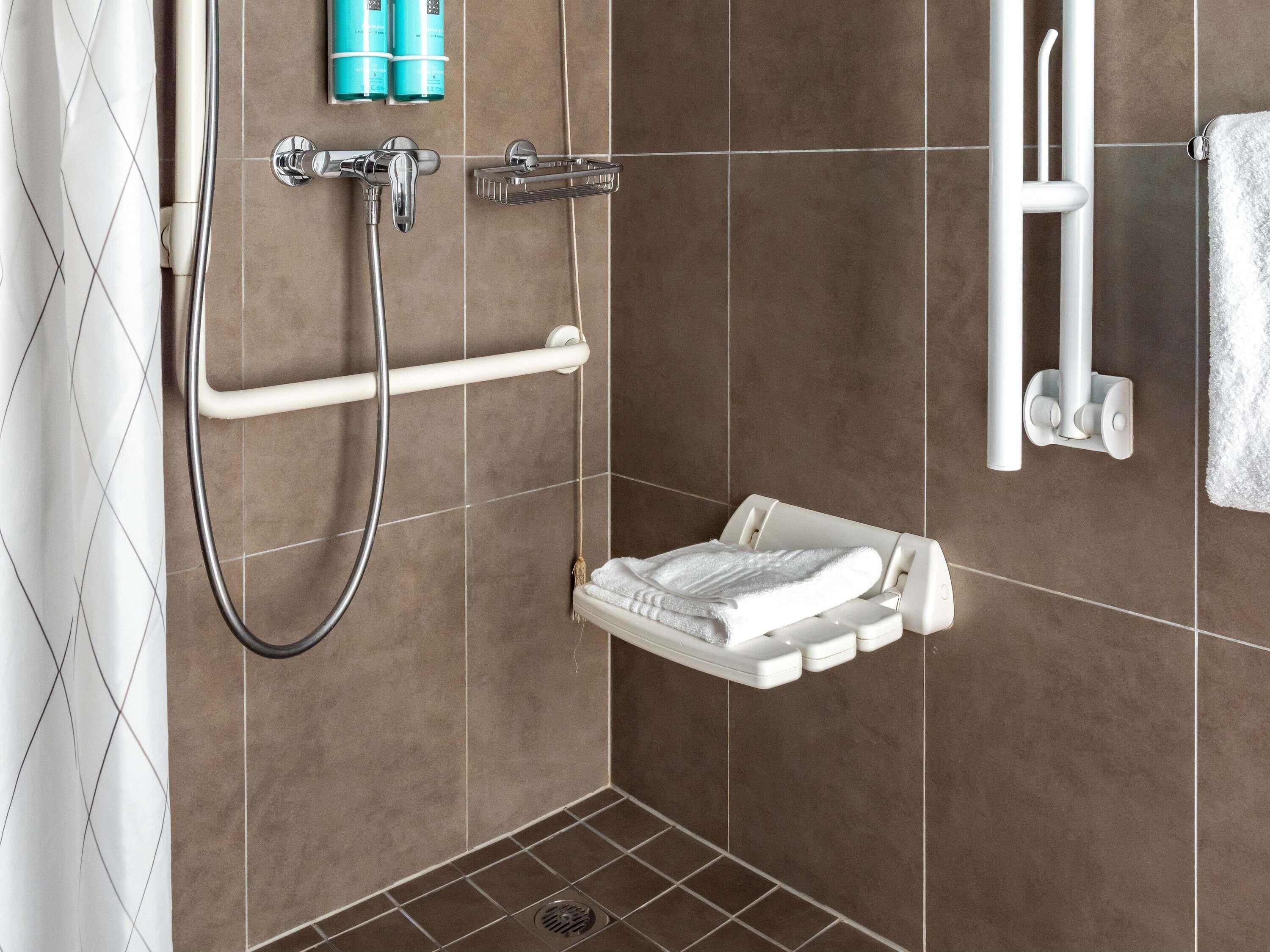 Un espace douche équipé d’un pommeau de douche à main et d’un porte-serviettes blanc.