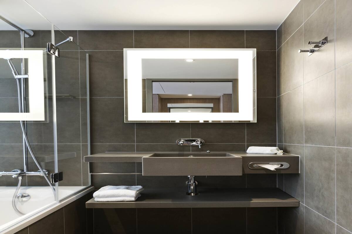 Een moderne badkamer met een grote spiegel, een wastafel en een douche.