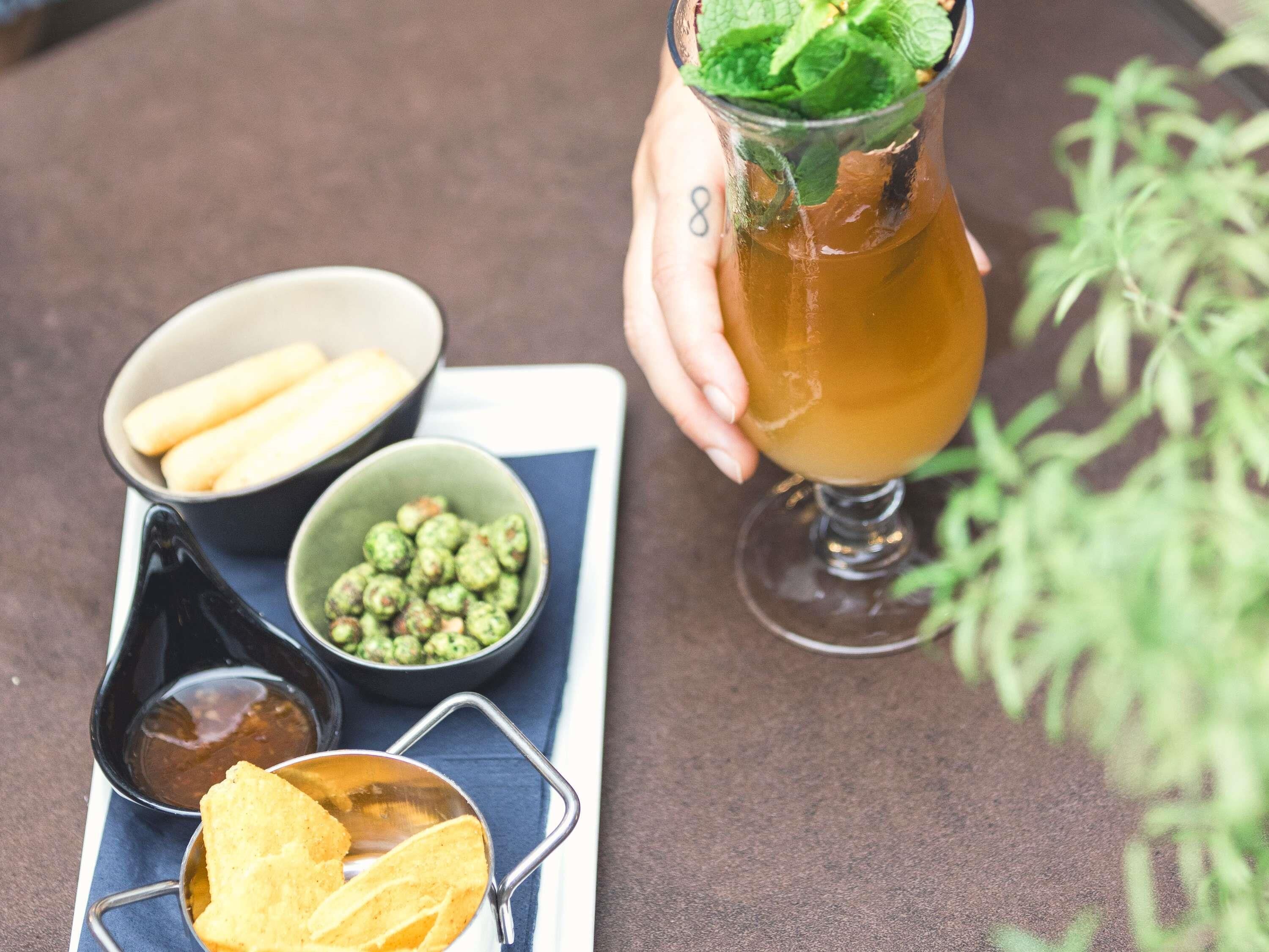 A tray with a drink, chips, and dips.