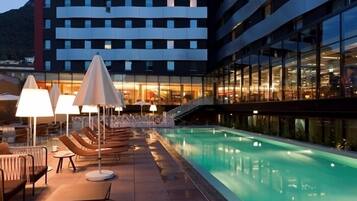 Relax by the rooftop pool surrounded by lounge chairs and tables.