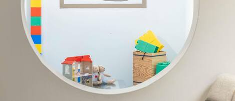 A circular mirror reflecting a child's play area with toys and a ship illustration.