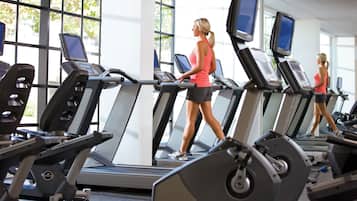 A gym with multiple treadmills, large windows, and a bright interior.