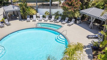 Zona de piscina con sillas de descanso, jacuzzi y señal de precaución.