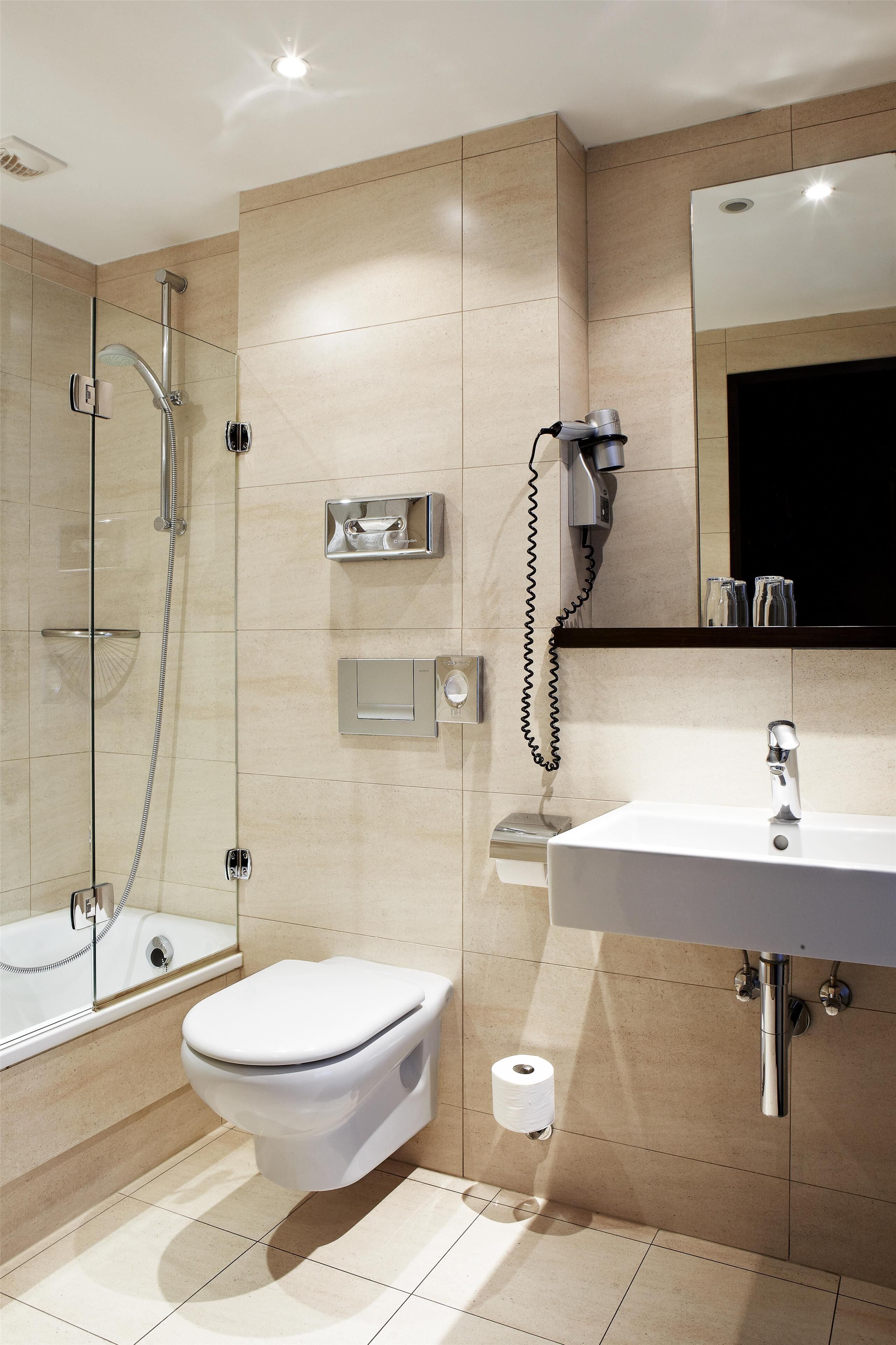 A modern bathroom with a glass-enclosed shower, a toilet, a sink, and a mirror.