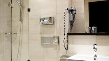 A modern bathroom with a glass-enclosed shower, a toilet, a sink, and a mirror.