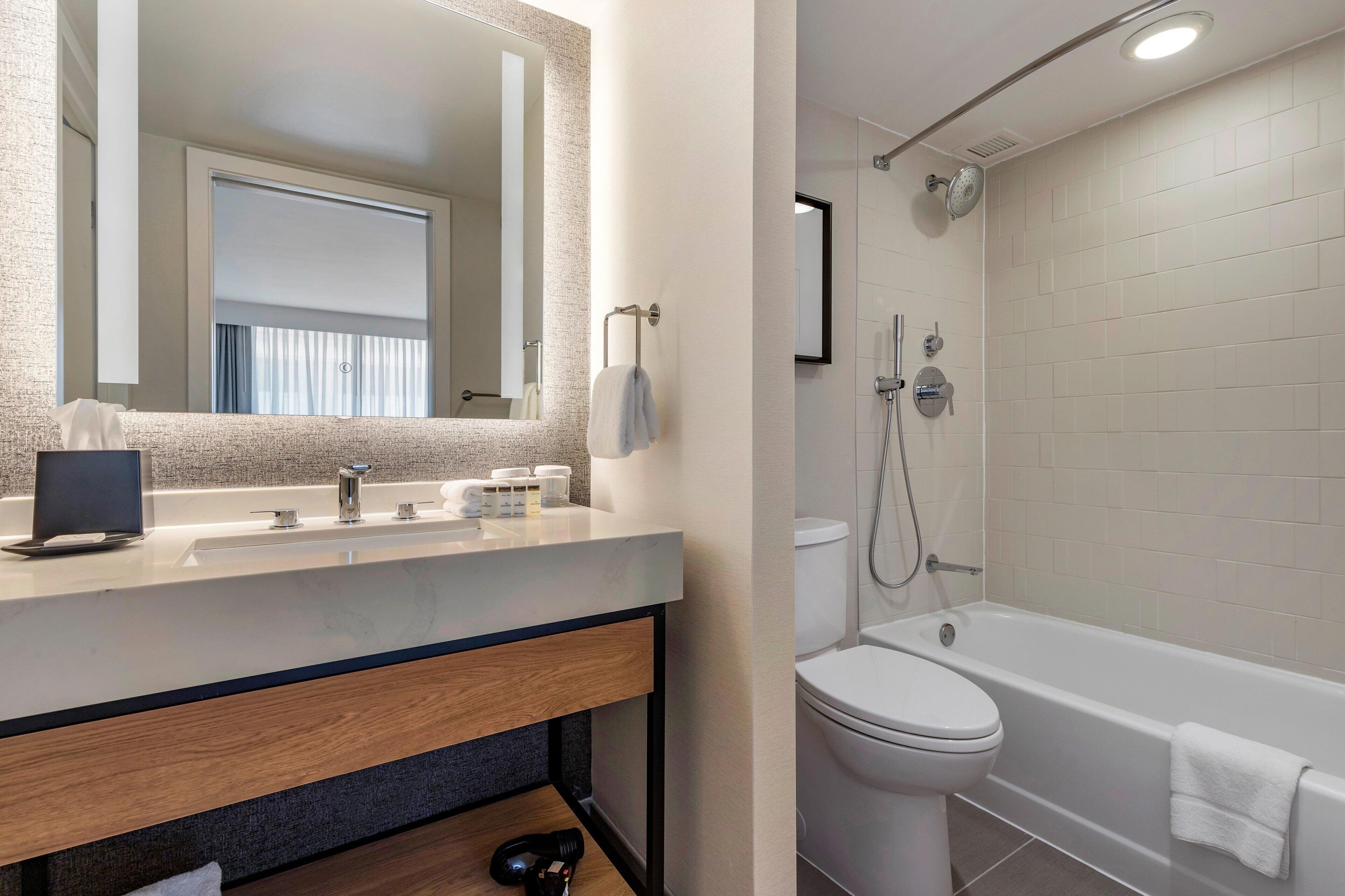 A modern bathroom with a sink, mirror, and a bathtub.