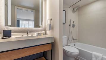 A modern bathroom with a sink, mirror, and a bathtub.