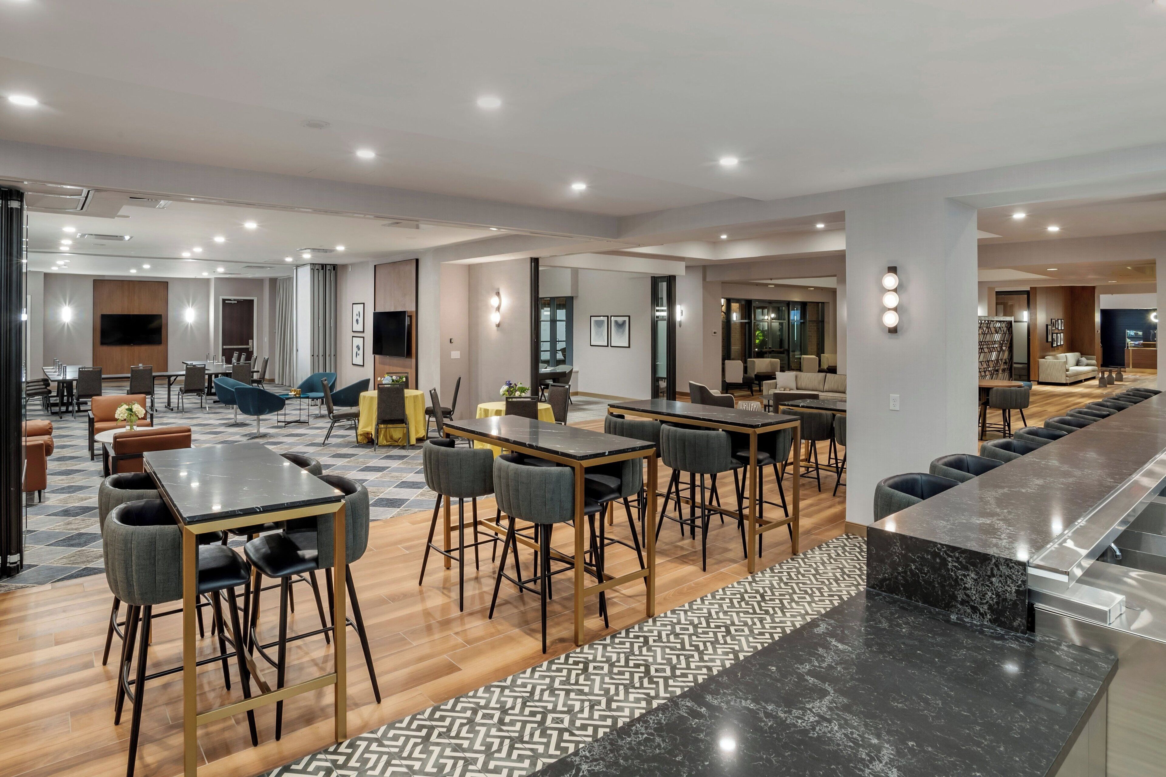A modern hotel lobby with a bar area, seating arrangements, and a patterned floor.