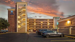 Un hotel de varios pisos con un cartel llamativo de Best Western, varios niveles de estacionamiento y un estacionamiento con varios coches.