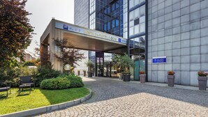 A hotel entrance with a covered walkway, potted plants, and a cobblestone path.