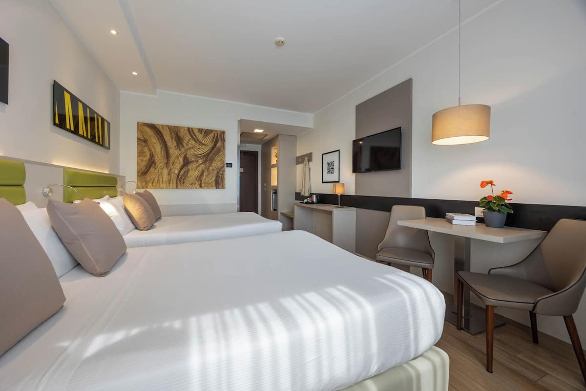 A hotel room with a bed, a desk, a chair, and a TV.