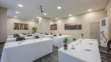 Un salón de conferencias con varias mesas, proyectores instalados en el techo y obras de arte enmarcadas en las paredes.