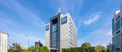 Un moderno edificio de hotel con un logotipo destacado, fachada de vidrio y un área de entrada bien cuidada.
