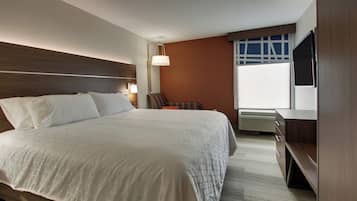 Una habitación de hotel con una cama grande, un escritorio, una silla, un televisor y una ventana.