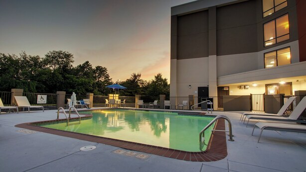 A swimming pool area with lounge chairs and a lifeguard stand.
