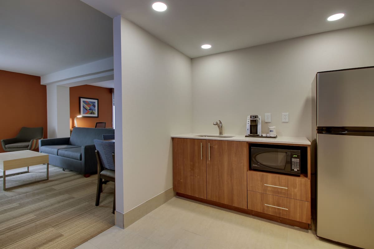 A compact kitchen with a microwave, coffee maker, and refrigerator.
