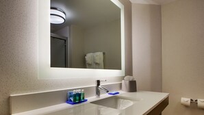 A modern bathroom with a large mirror, a sink, and a towel rack.