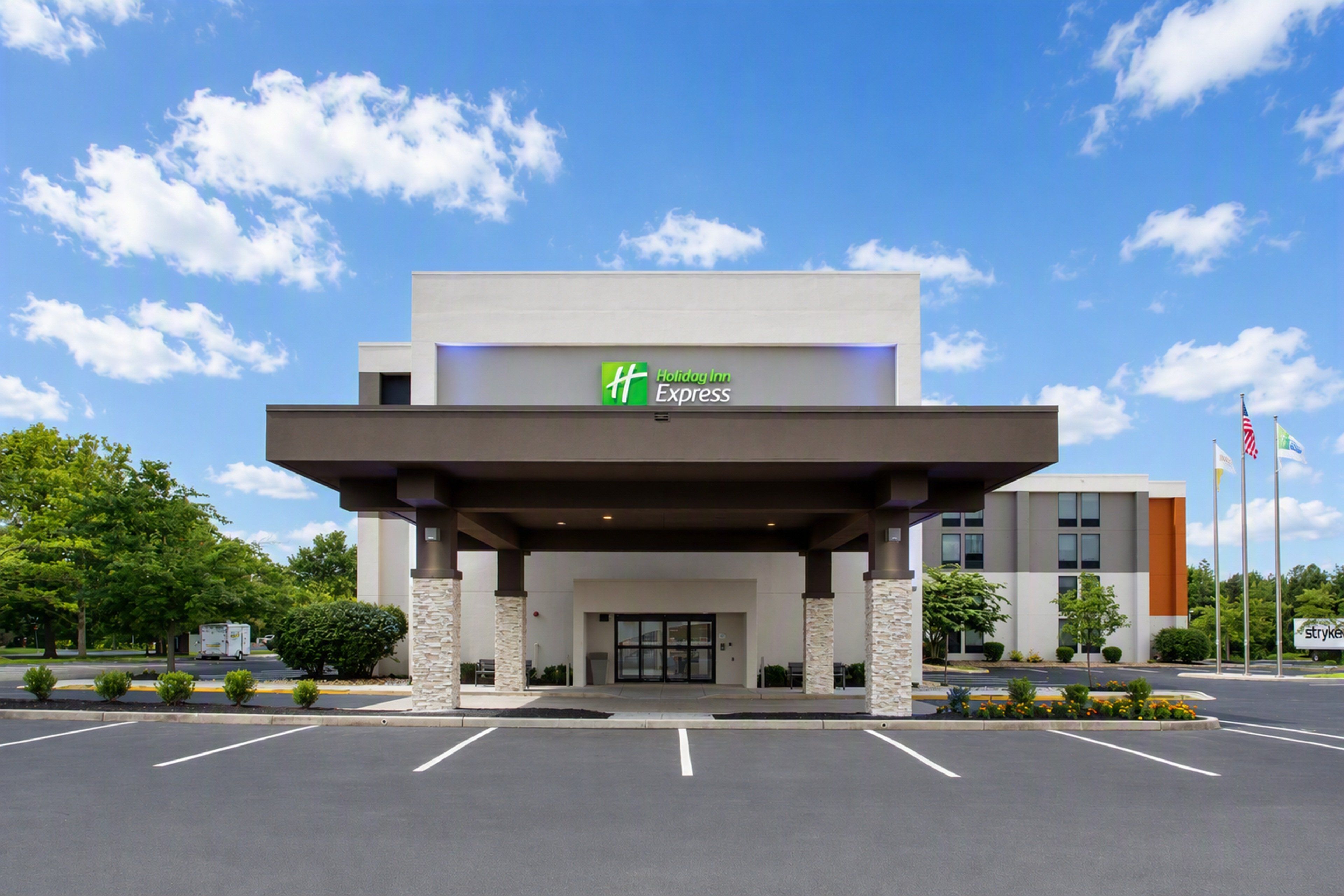 A Holiday Inn Express building with a covered entrance, parking lot, and flags.