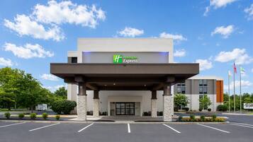 A Holiday Inn Express building with a covered entrance, parking lot, and flags.