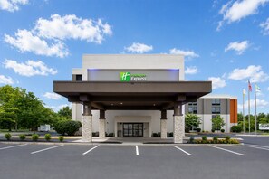 Holiday Inn Express -hotellin rakennus, jossa on katettu sisäänkäynti, pysäköintialue ja lipputangot.