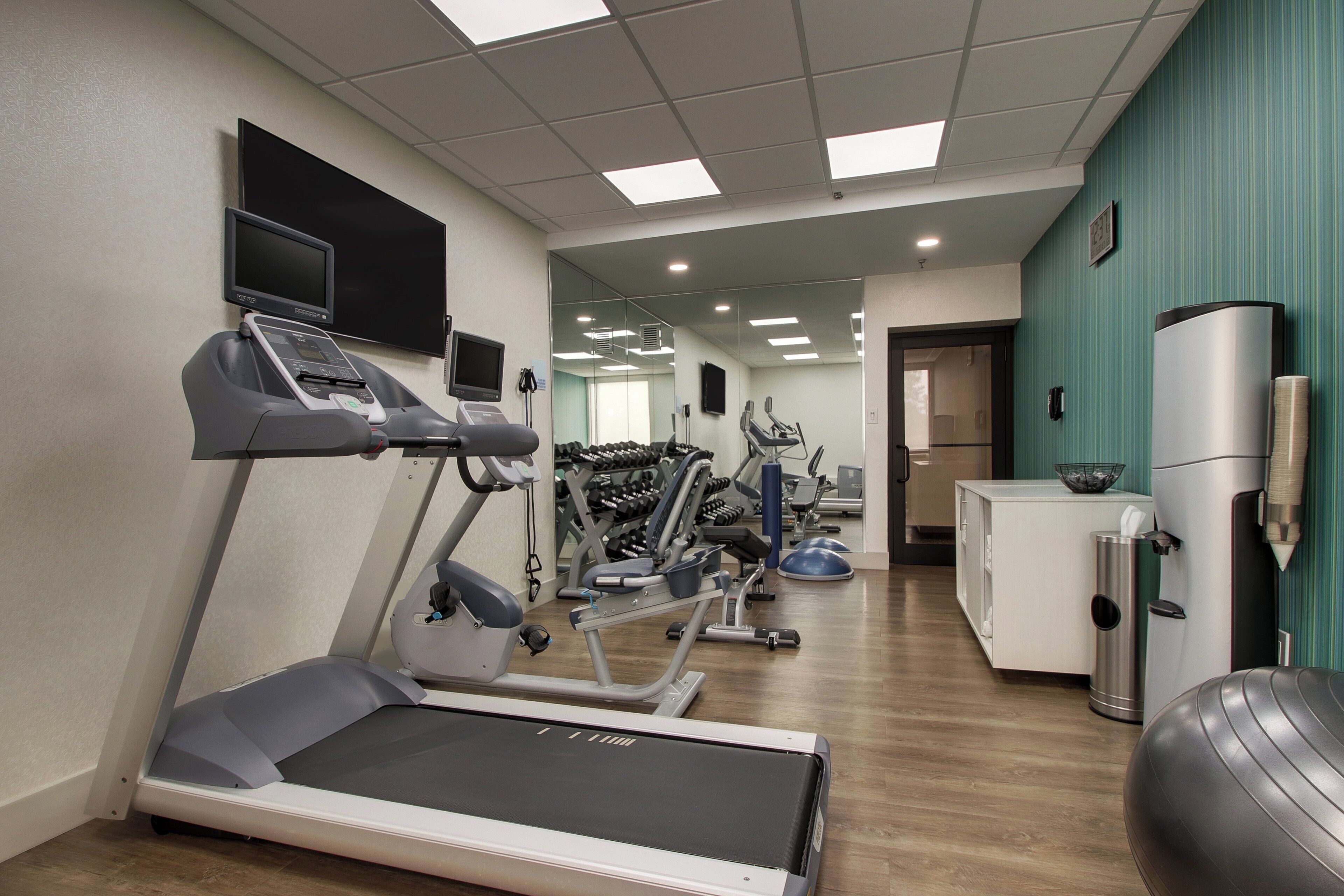 A gym with treadmills, exercise bikes, and weights.