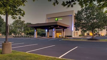 Edifício Holiday Inn Express com entrada coberta, estacionamento e vegetação ao redor.