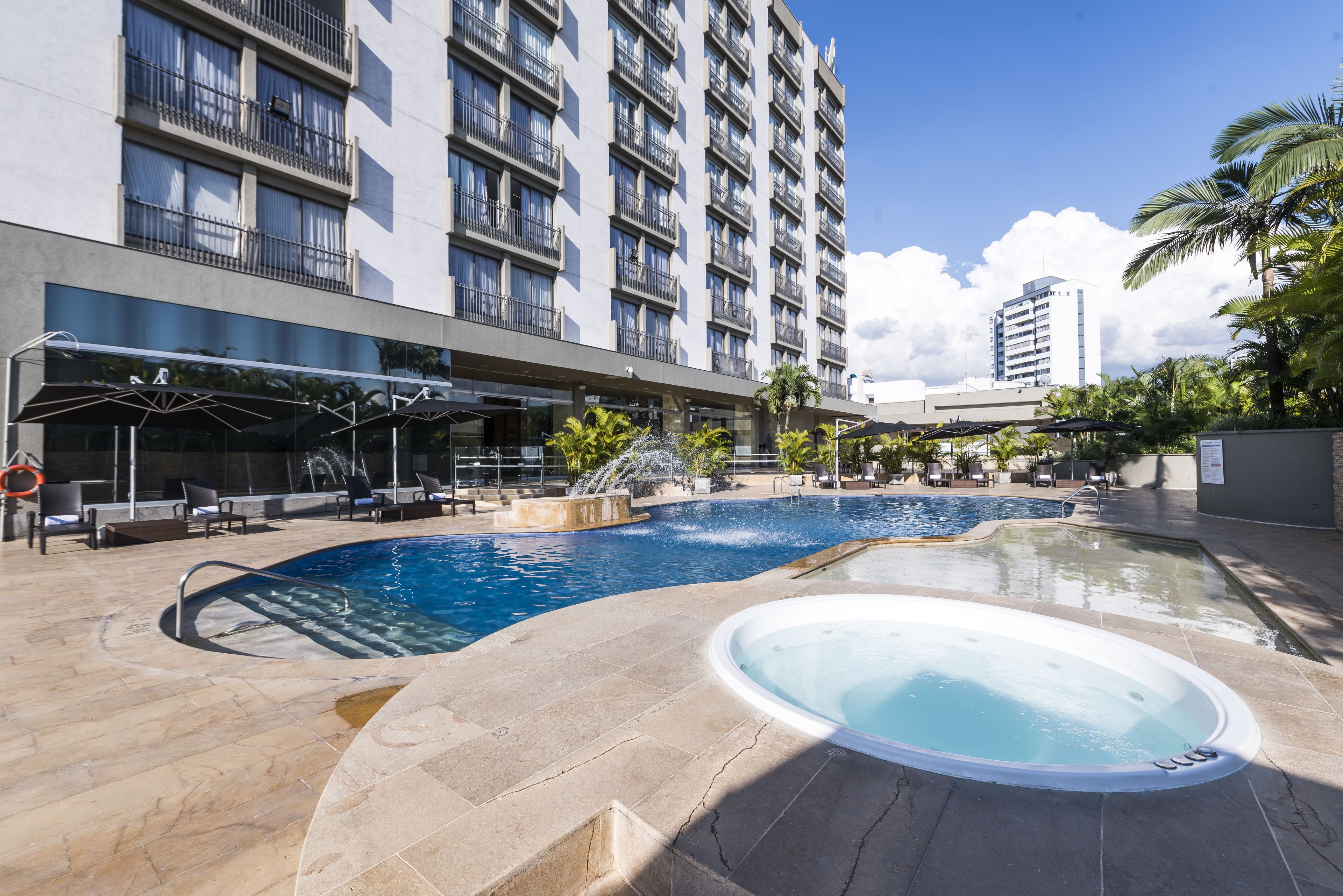 A hotel with a swimming pool, lounge chairs, and a hot tub.