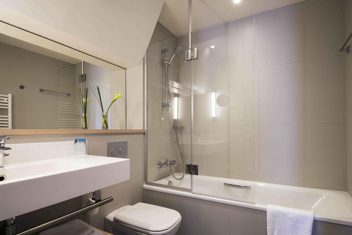 Une salle de bain moderne avec une douche à parois de verre, un lavabo blanc et des toilettes.