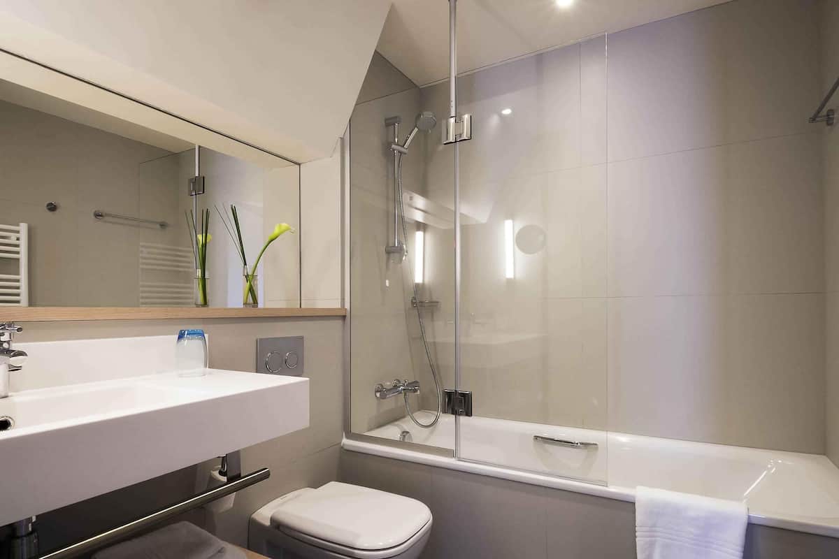 A modern bathroom with a glass-enclosed shower, a white sink, and a toilet.